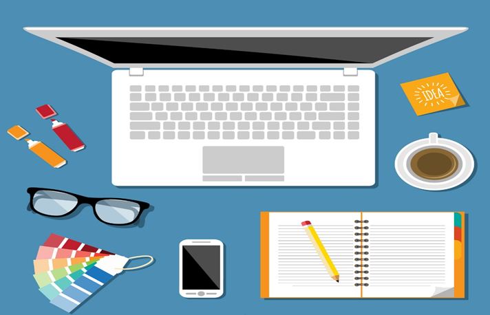 Computador, celular, óculos em uma mesa e bloquinho de anotações